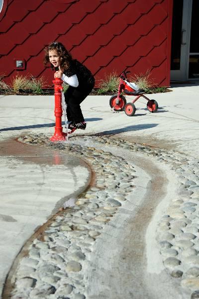 child playing with water pump outside at the early learning center